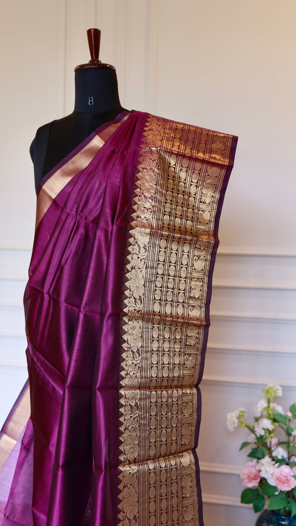 Close-up image highlighting the detailed traditional motifs woven into the golden zari pattu border of the magenta Mangalagiri saree.