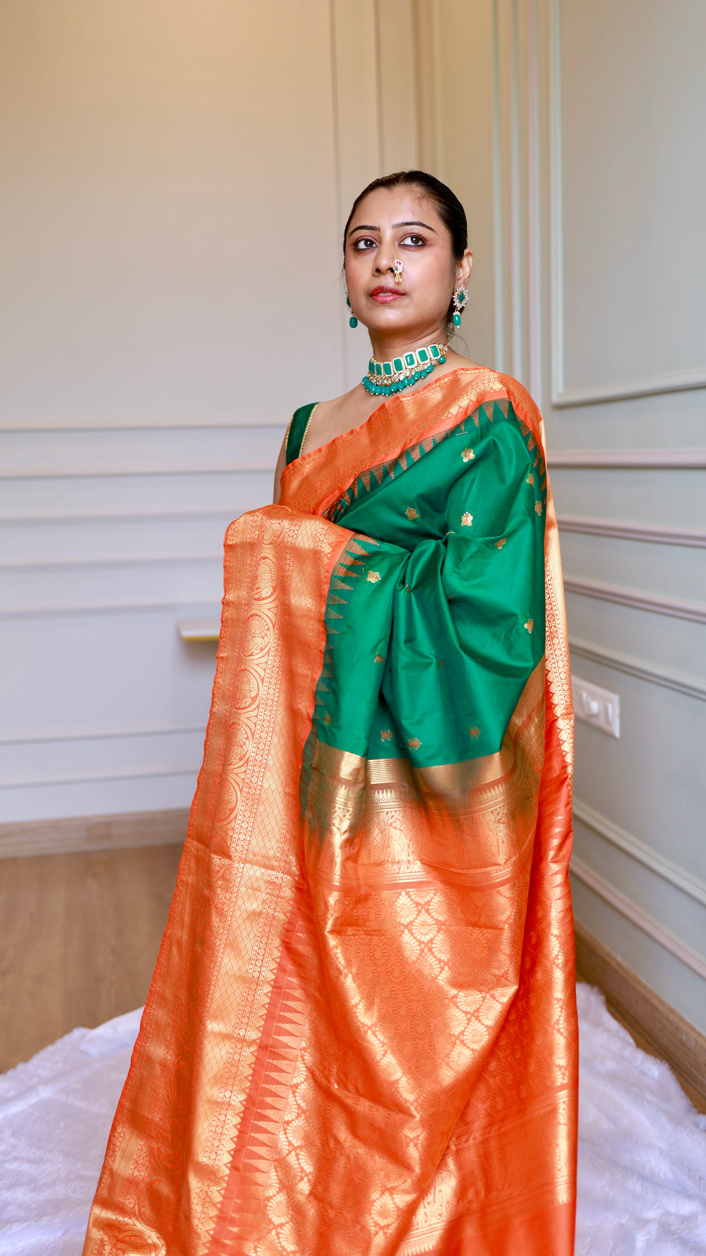 Close-up view of model draped in bottle green semi Gadwal saree with gold choker necklace and traditional nose ring.