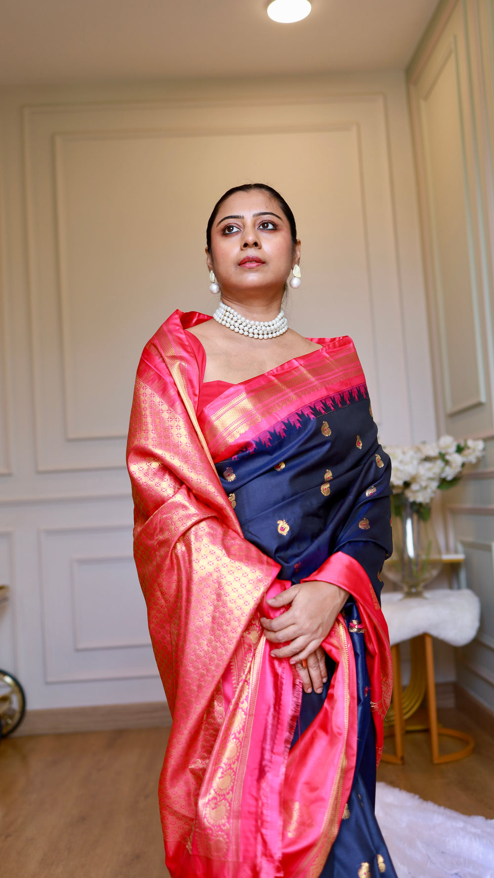 Medium shot of model wearing navy blue semi Gadwal silk saree with rani pink border paired with pearl necklace