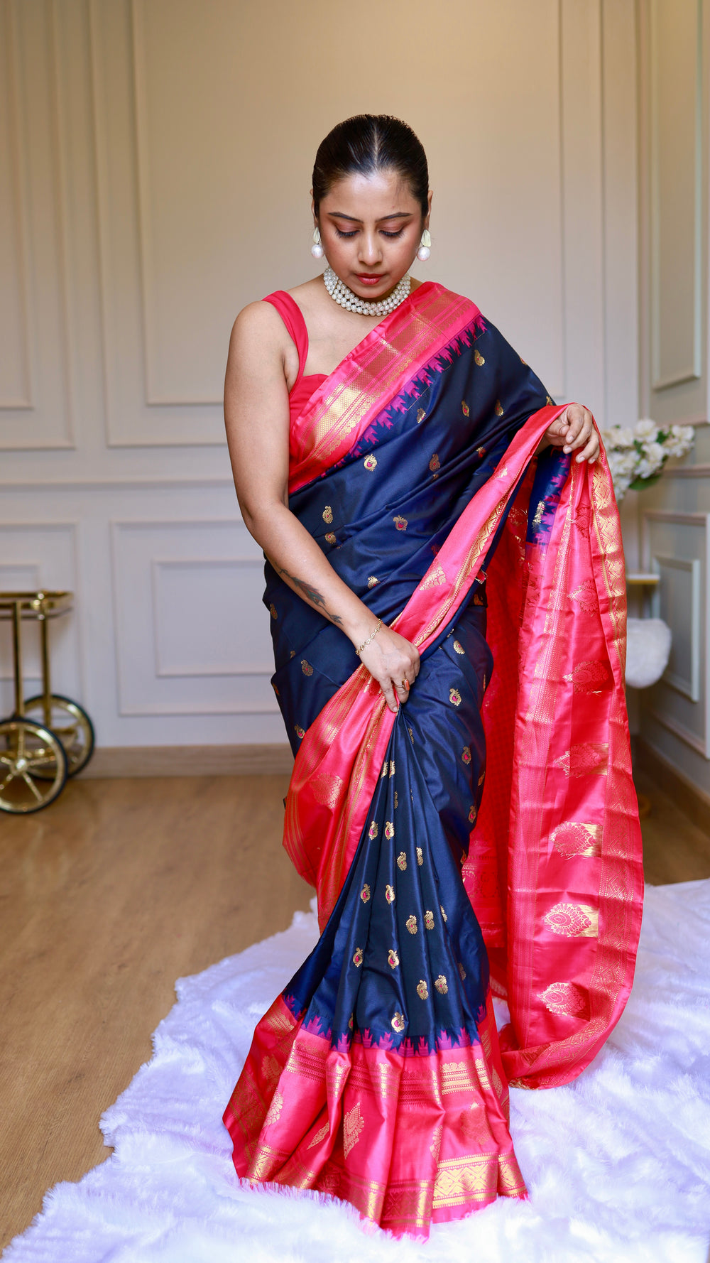 Full body shot of model wearing midnight blue semi Gadwal saree displaying pleats and contrasting pink zari pallu