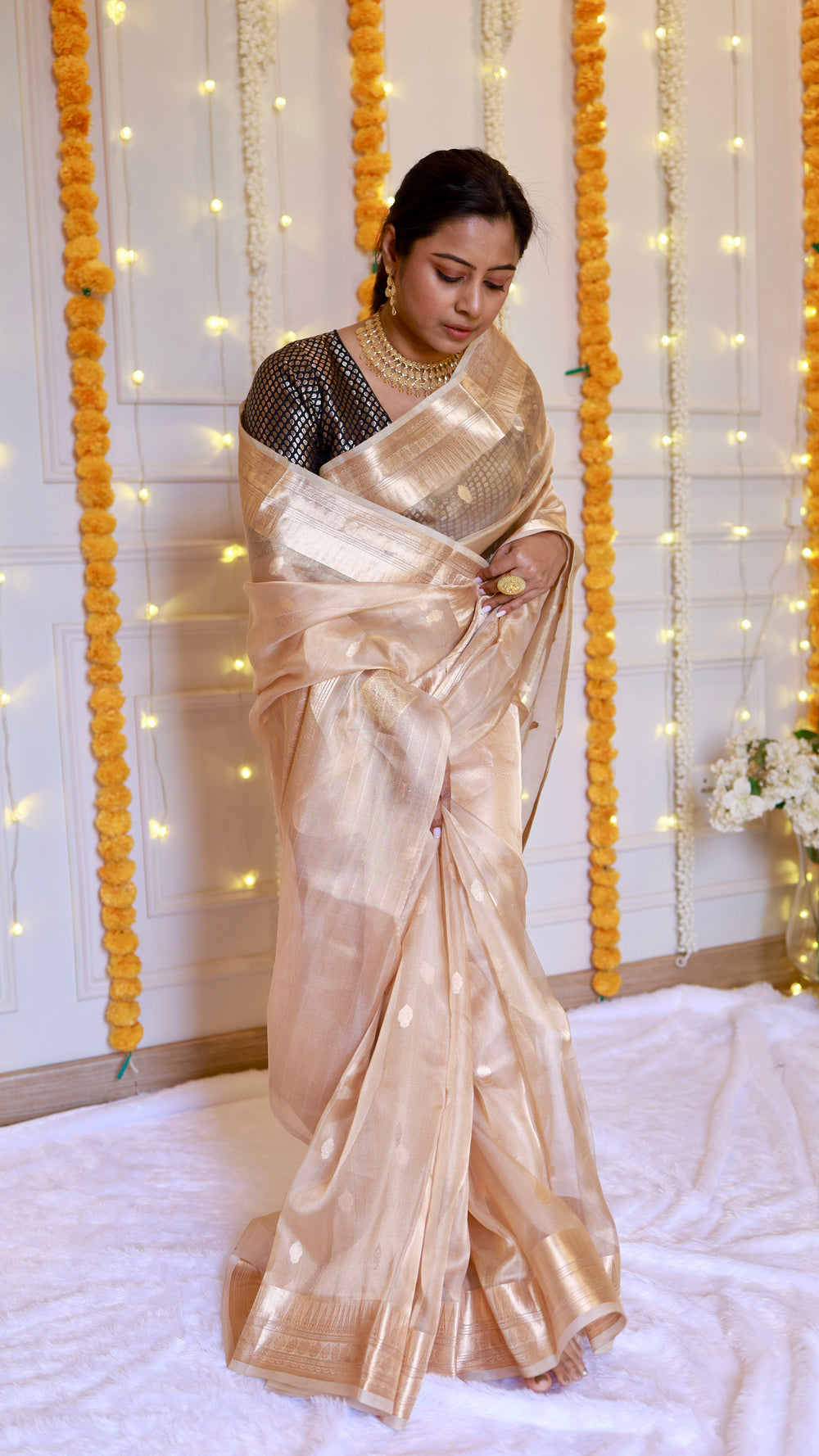 Standing pose displaying the complete drape, pallu fold, and luminous metallic texture of the champagne gold tissue saree.