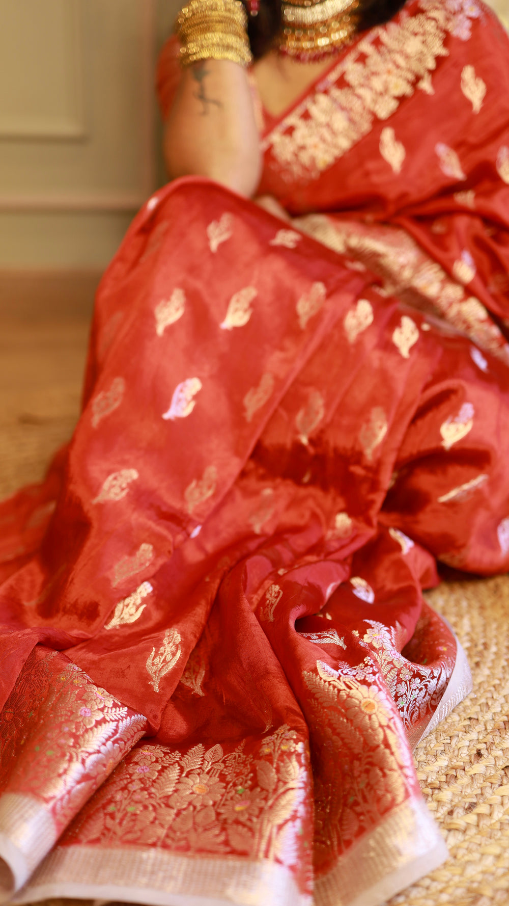 High-angle close-up highlighting the soft pleats, silver zari leaf motives, and fluid texture of the red georgette saree fabric.