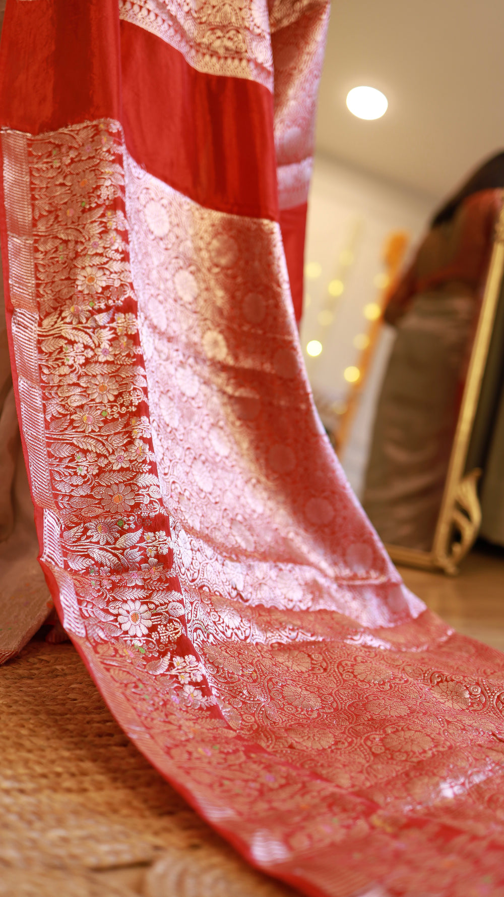 Extreme close-up of the fine silver and gold zari floral pattern along the red pallu of a Banarasi georgette saree.