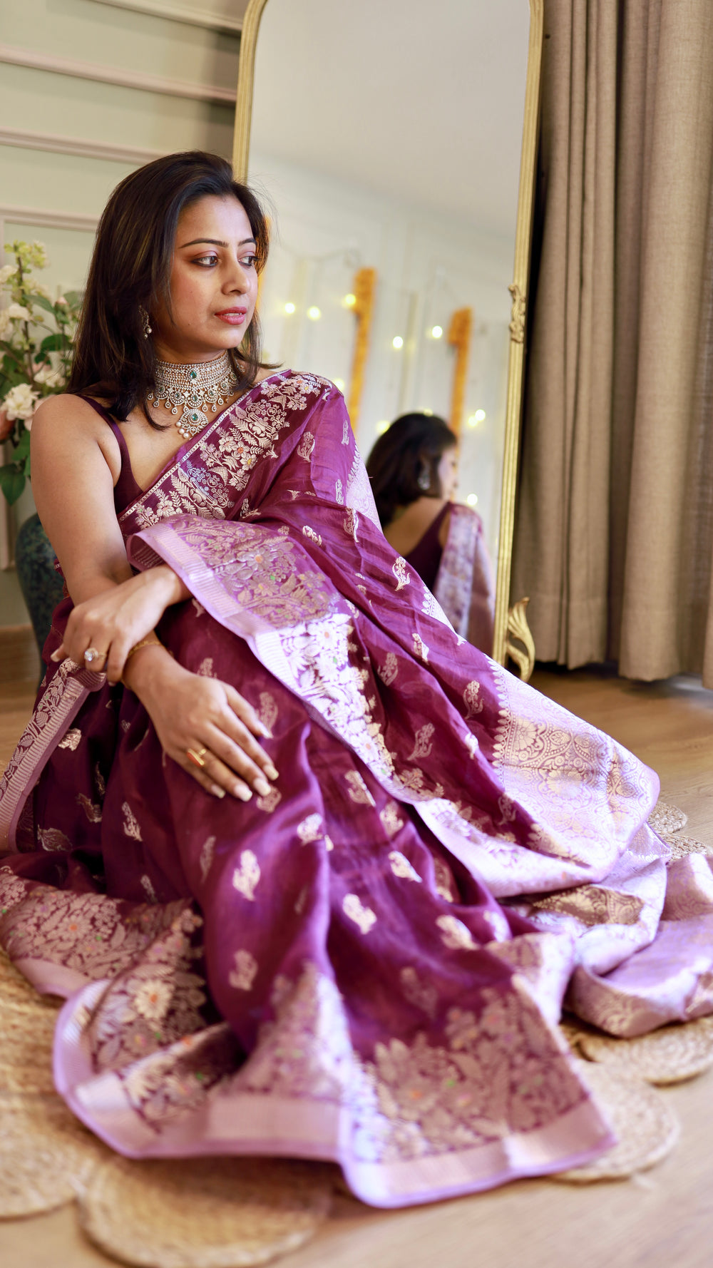 Elegant portrait shot of a model posing near a mirror in a regal purple georgette Banarasi silk-style saree.