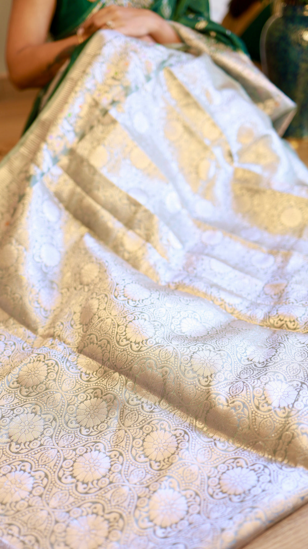 Detailed view of the silver zari woven pallu and pattern of the emerald green Banarasi georgette saree.