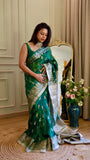 Full-length view of a woman showcasing the drape and silver zari pallu of the emerald green georgette Banarasi saree.
