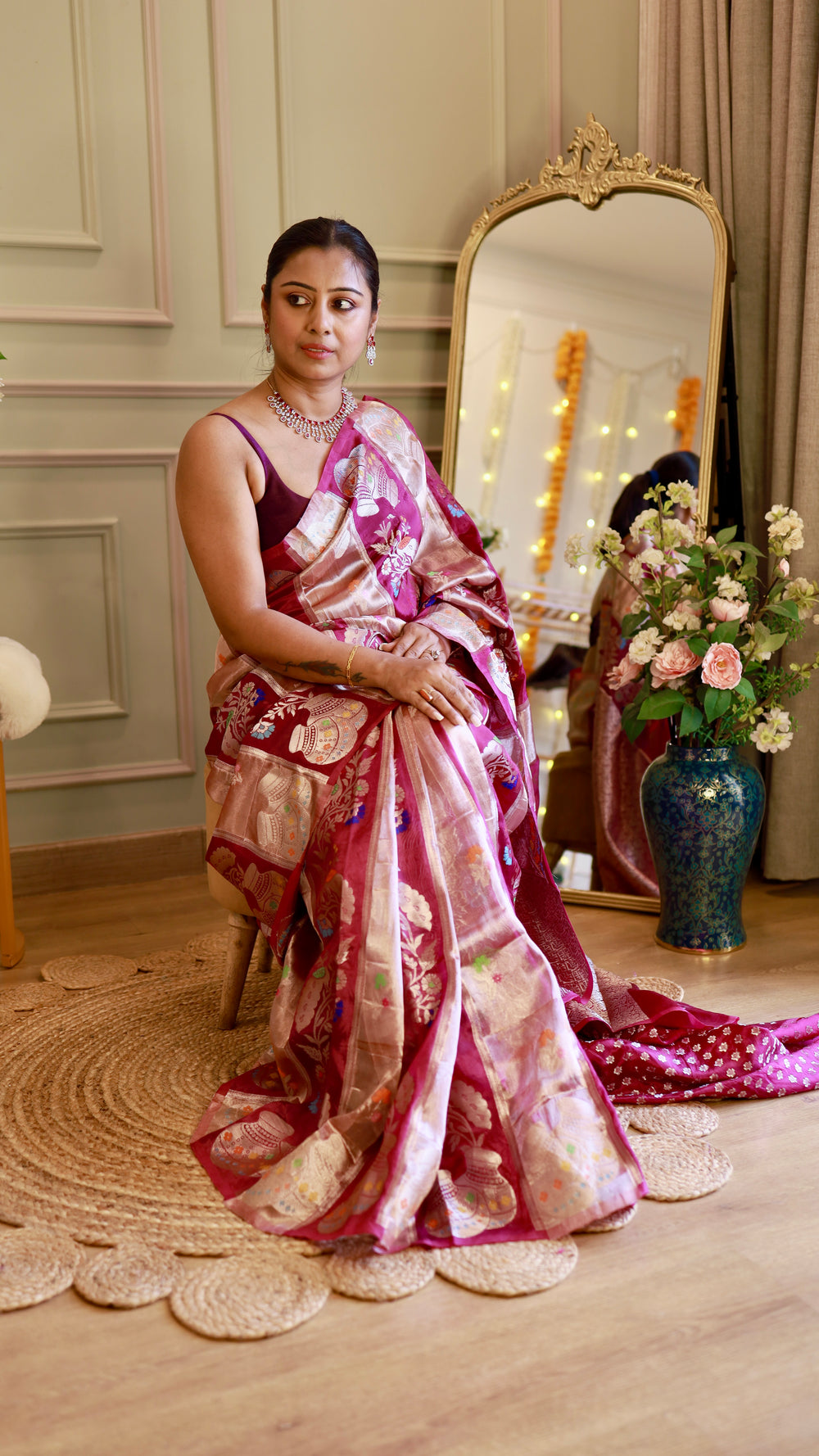 Seated front pose of model demonstrating the rich silver zari pallu and soft sheen of the magenta Munga Banarasi saree in warm indoor lighting.