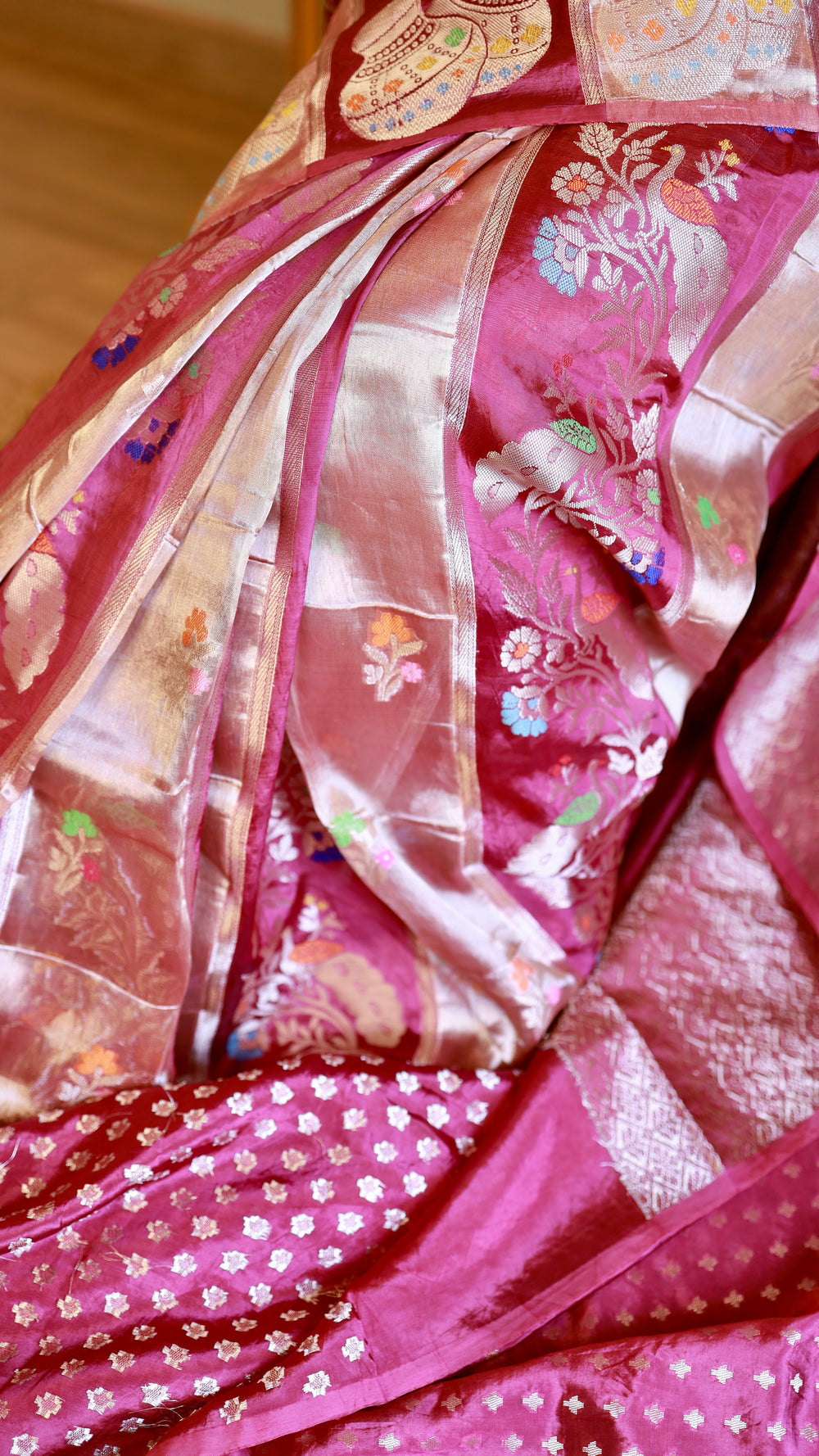 High-resolution close-up detail of the woven silver zari floral meenakari work and Kalash motifs on the magenta Munga Banarasi saree drape.