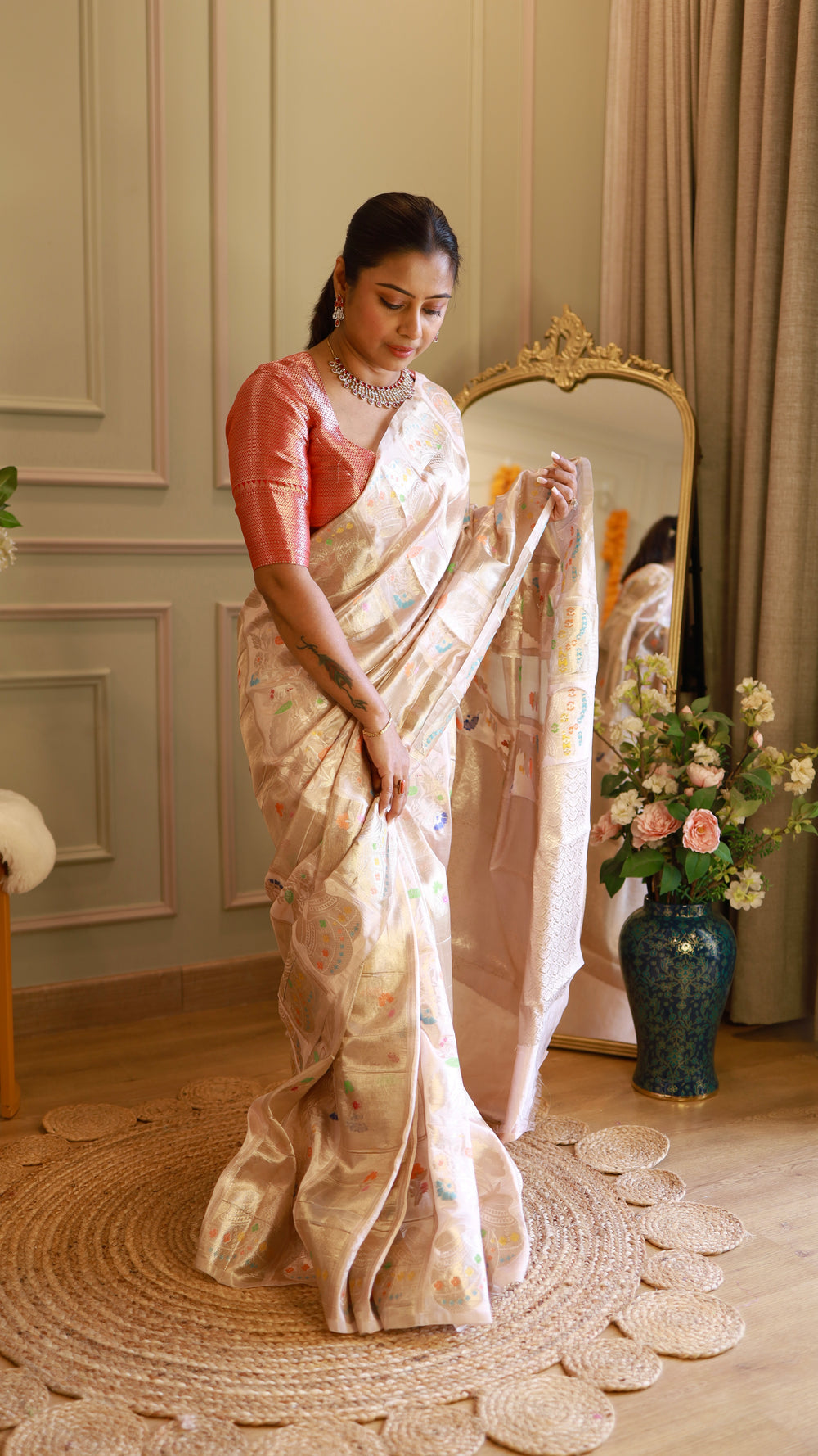 Model sitting gracefully to display the soft drape, sheen, and pleats of the ivory Munga Banarasi silk saree.