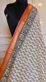 Close-up view of off-white Maheshwari silk saree showing black floral block print and rust red gold zari border