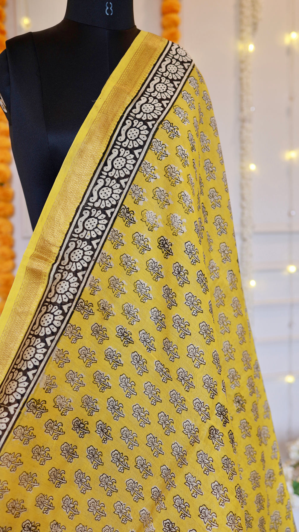 Detailed view of intricate black floral block print booti motifs and gold woven zari border on yellow silk saree