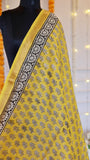 Detailed view of intricate black floral block print booti motifs and gold woven zari border on yellow silk saree