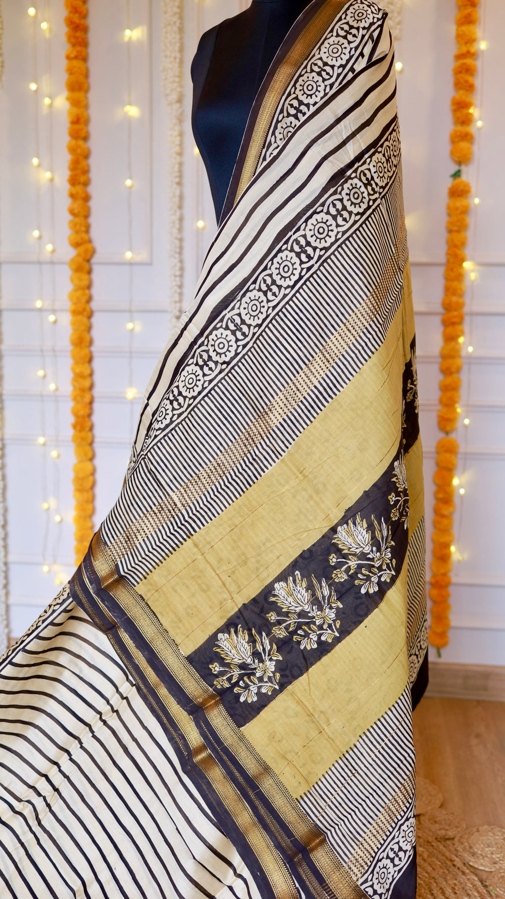 Richly patterned pallu of Maheshwari Silk Saree showing floral block prints on mustard and black panels.