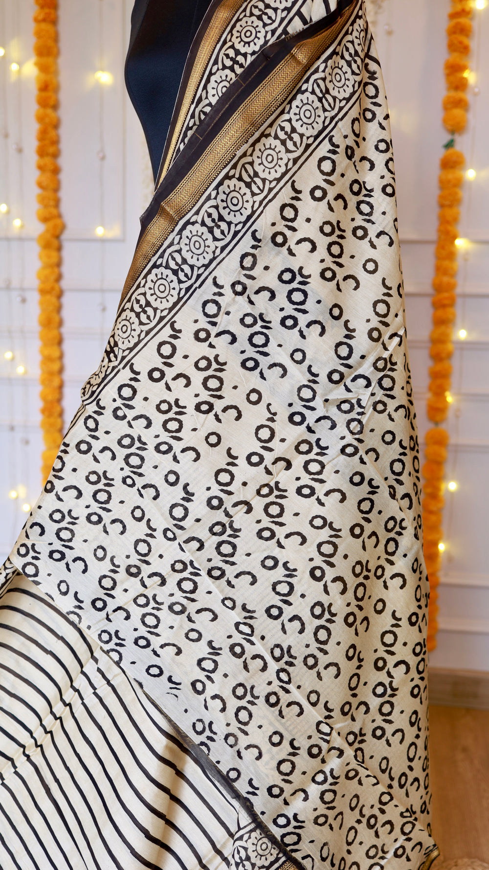 Detailed view of the circular block-print pattern on an off-white handloom silk saree fabric.