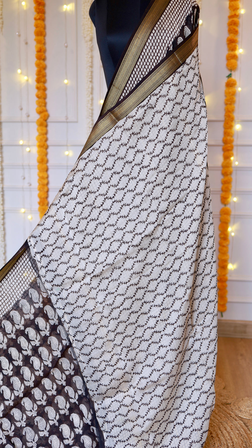 Close-up view of off-white wave pattern and black paisley block-printed drape on a Black Maheshwari Silk Saree with golden zari border.