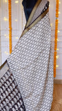 Close-up view of off-white wave pattern and black paisley block-printed drape on a Black Maheshwari Silk Saree with golden zari border.