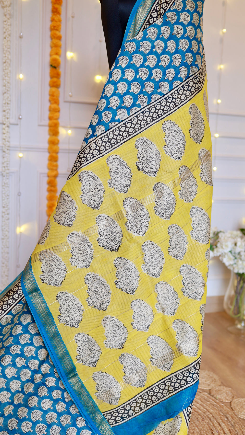 Vibrant yellow pallu of Maheshwari Silk Saree featuring black paisley block prints and cerulean blue floral motifs.