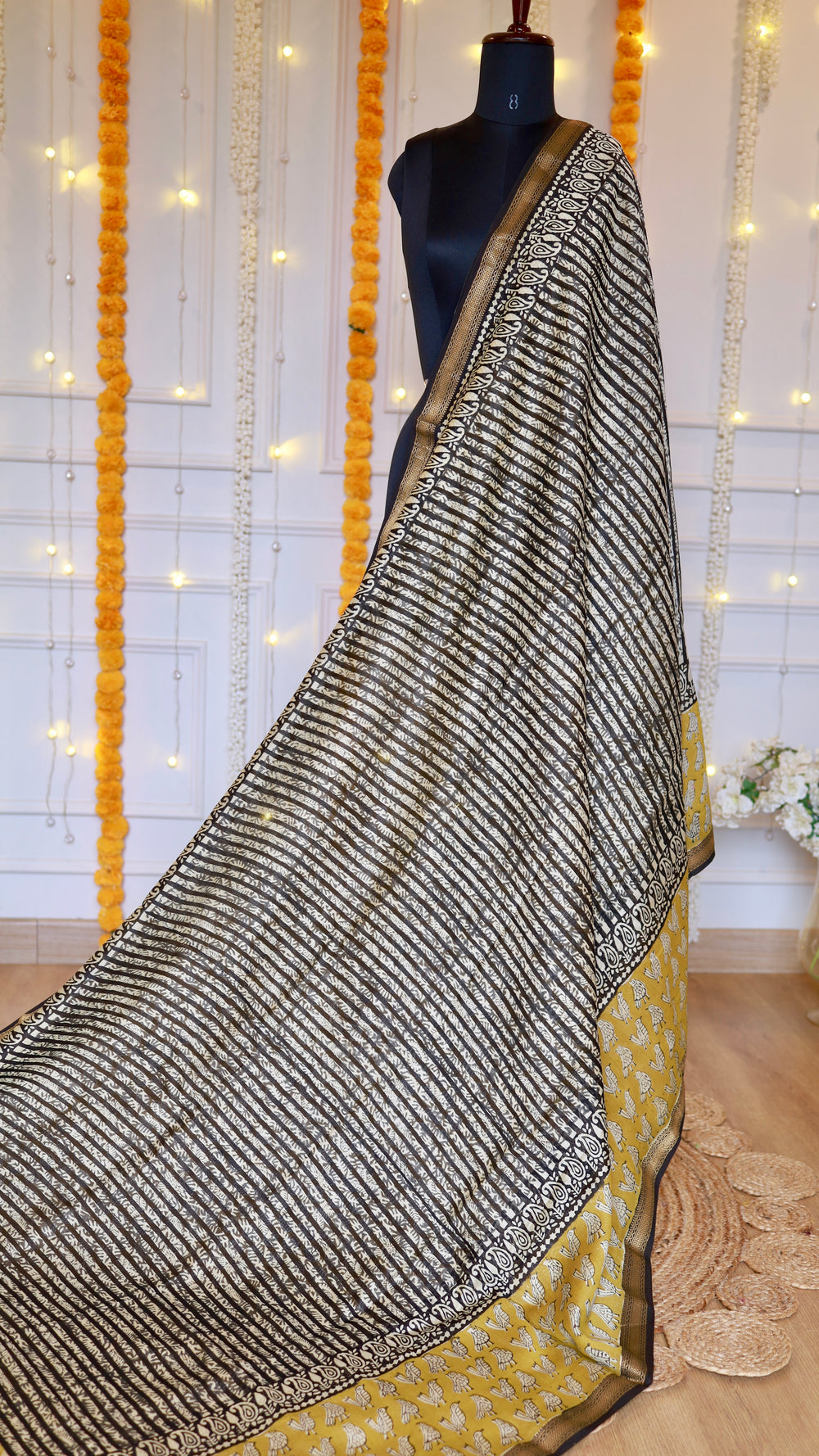 Full drape view of black and off-white diagonal stripe pattern on Maheshwari silk saree pallu with mustard accent border.
