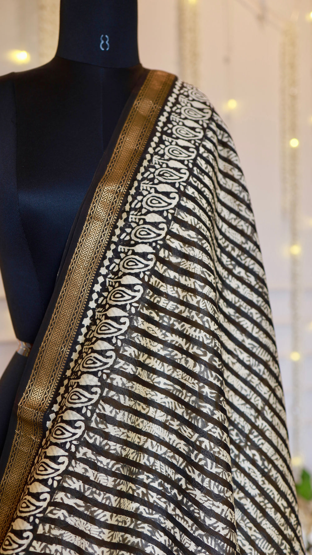 Close-up of black and white wavy hand block print design with traditional zari border on Maheshwari silk fabric.
