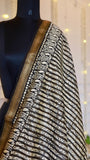 Close-up of black and white wavy hand block print design with traditional zari border on Maheshwari silk fabric.