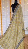 Mustard yellow hand block printed Maheshwari silk saree with black paisley woven zari border draped on a mannequin.