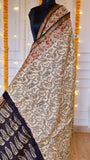Hand block printed Maheshwari silk saree draped on mannequin featuring off-white paisley body, red floral borders, and woven golden zari edging.
