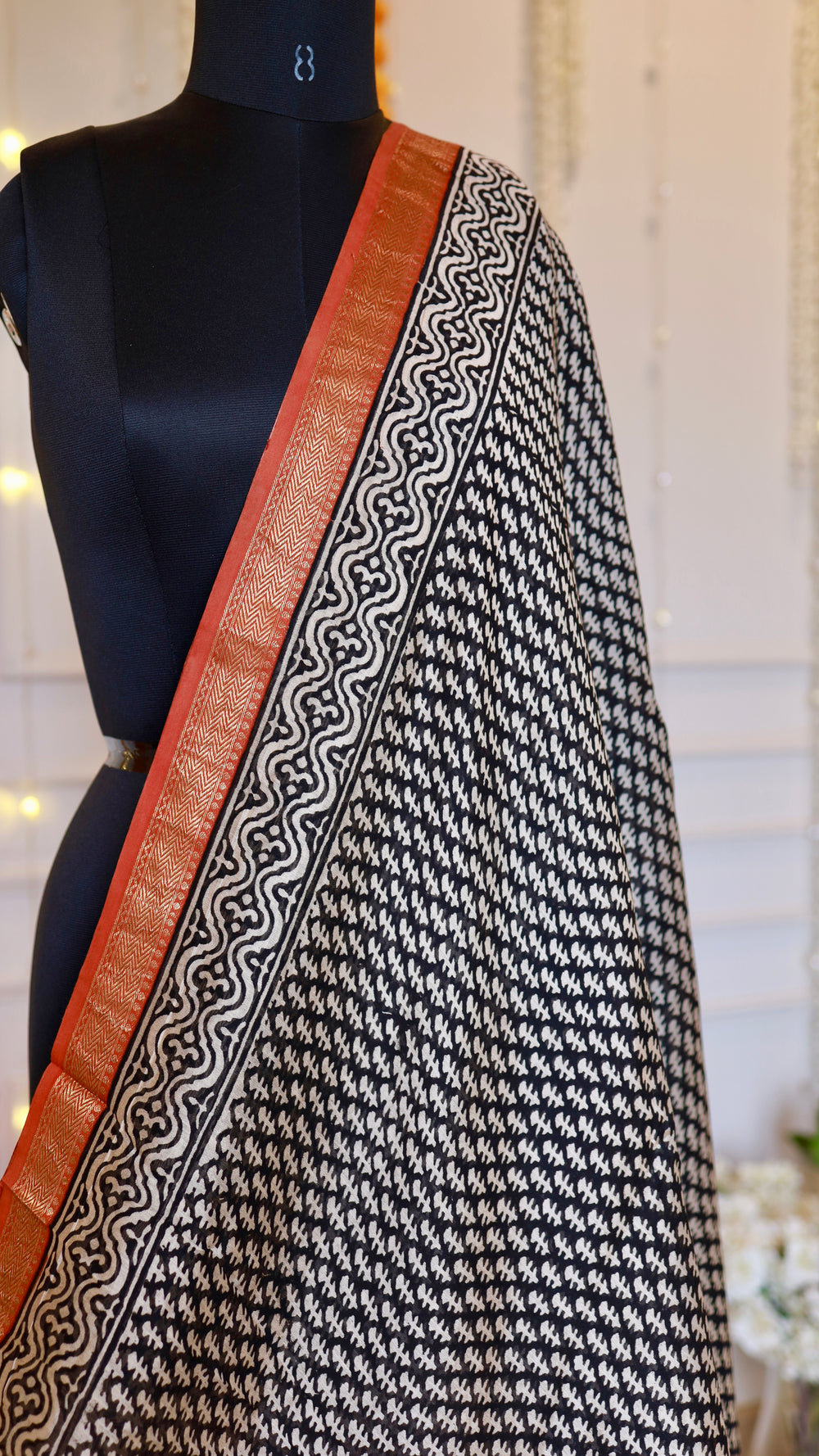 Close-up of black geometric printed body pattern and rust-orange zari border of Maheshwari silk saree