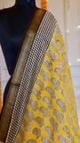 Upper shoulder drape of Mustard Yellow Maheshwari Silk Saree displaying paisley block prints and geometric grid border.