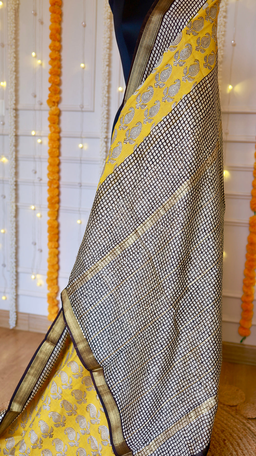 Close-up of Yellow Maheshwari Silk Saree showing black grid pattern border and yellow paisley printed panel with woven zari trim.
