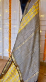 Close-up of Yellow Maheshwari Silk Saree showing black grid pattern border and yellow paisley printed panel with woven zari trim.