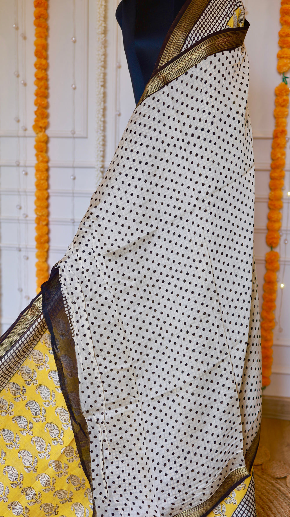 Detail view of the off-white polka dot body section and zari border on the Yellow Maheshwari Silk Saree.