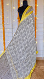 Maheshwari Silk Saree featuring black and off-white geometric block print body with a bright yellow zari border draped on a mannequin.