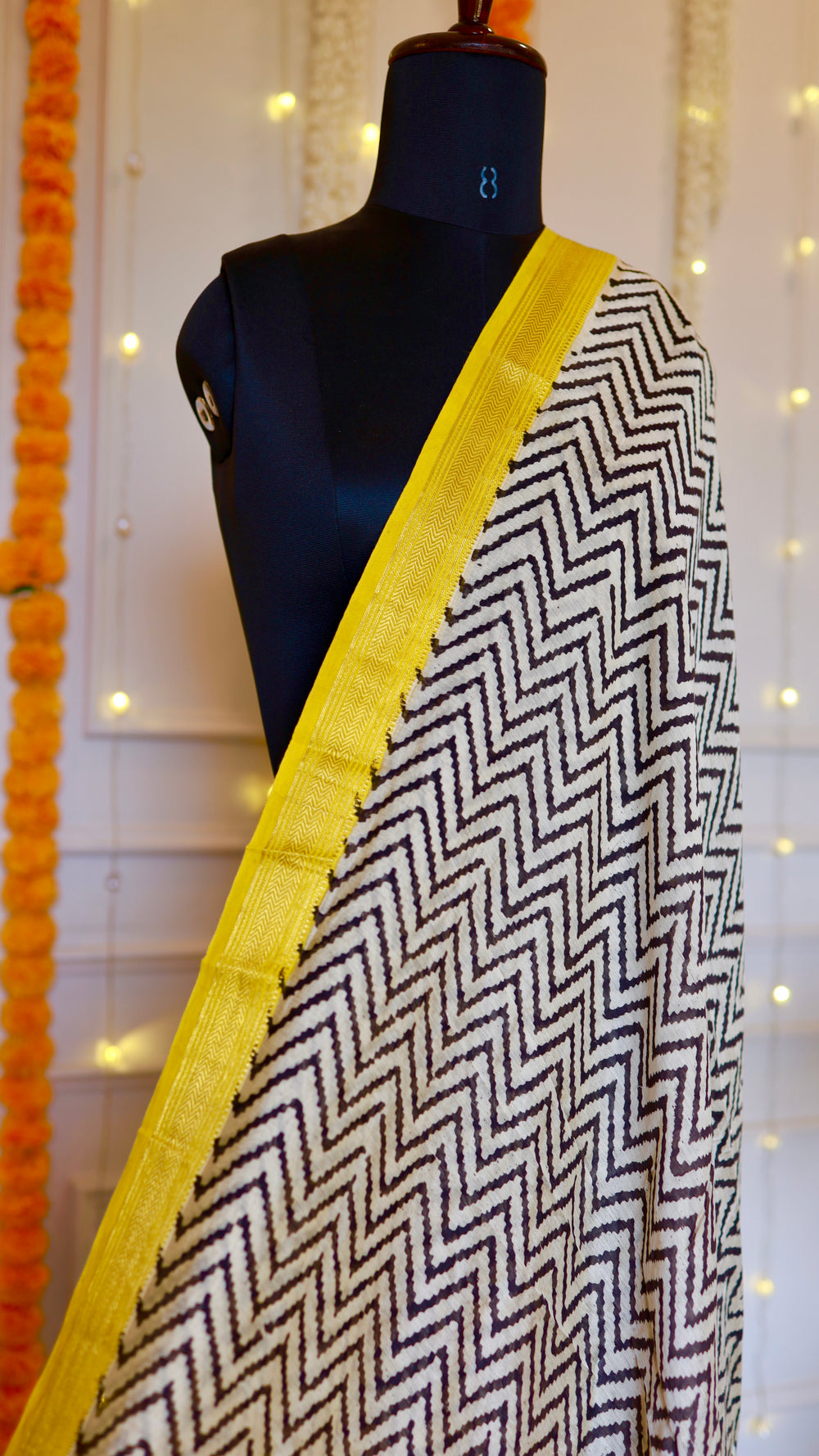 Close-up shot of the monochrome chevron zigzag pattern and woven yellow border on the Maheshwari Silk Saree.
