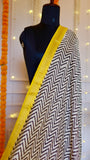 Close-up shot of the monochrome chevron zigzag pattern and woven yellow border on the Maheshwari Silk Saree.