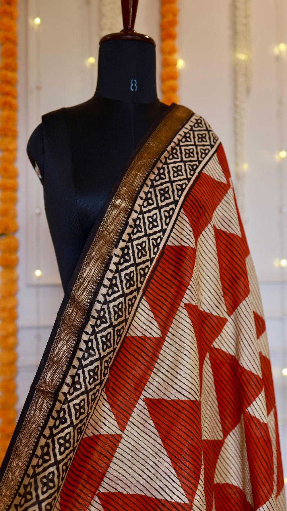Close-up view of rust orange striped triangle pattern with woven zari border on Maheshwari silk saree