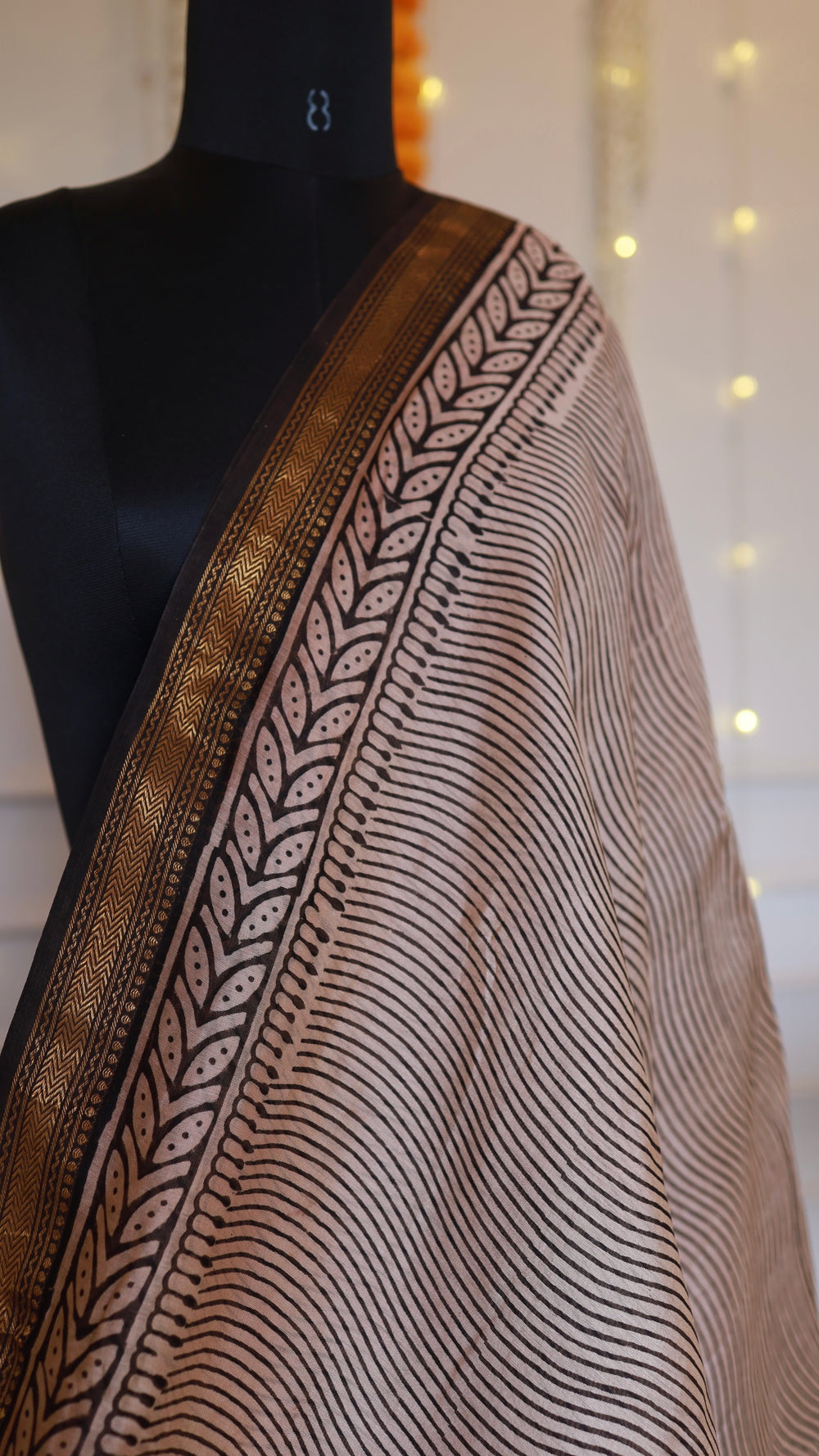 Close up view of Maheshwari silk saree drape showing leaf printed border and antique gold woven zaripatti