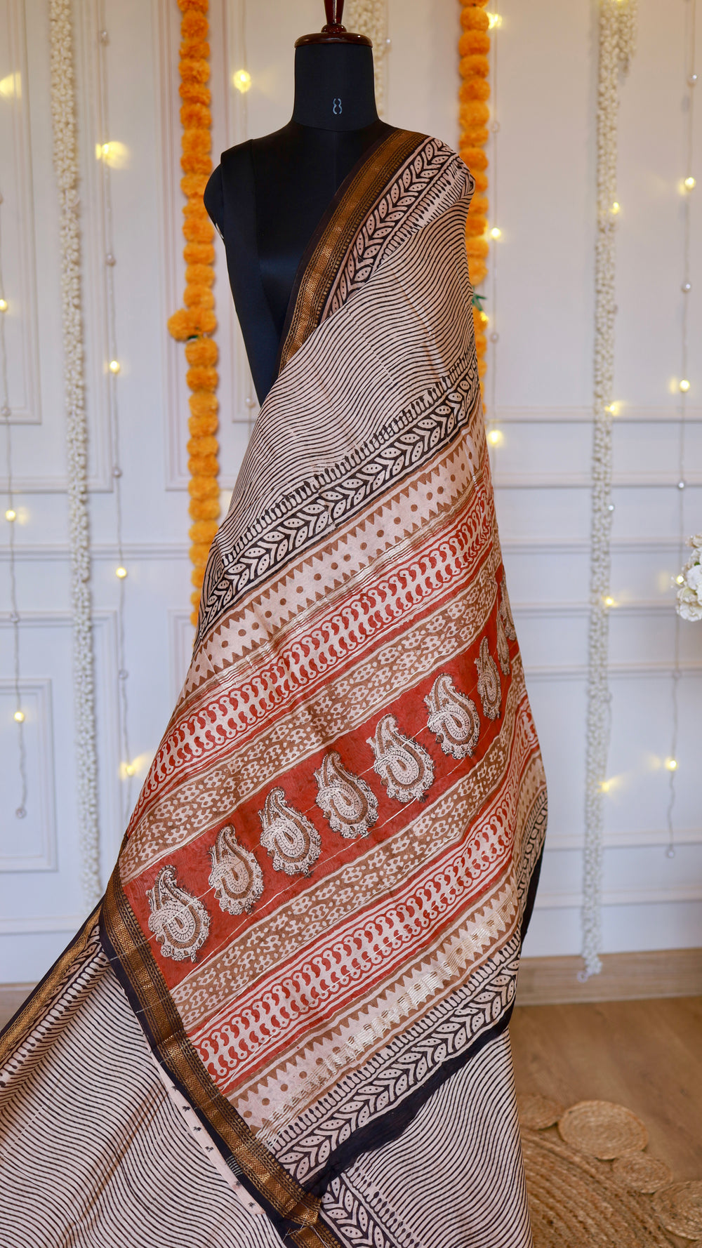 Detailed view of rust red pallu featuring hand block printed paisley motifs on beige Maheshwari silk drape