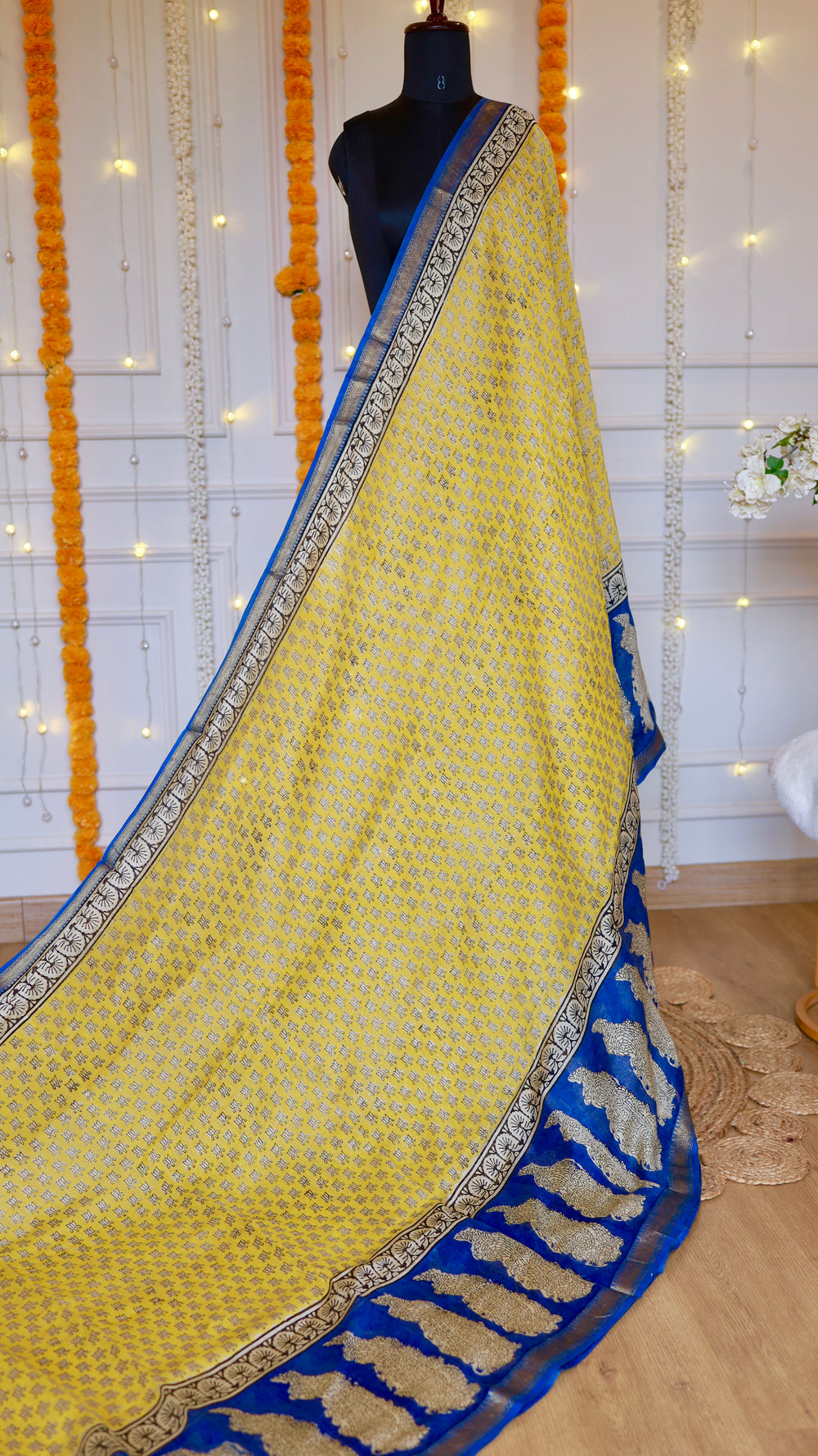 Full length drape of mustard yellow Maheshwari silk saree displaying royal blue contrast pallu and delicate border layout.