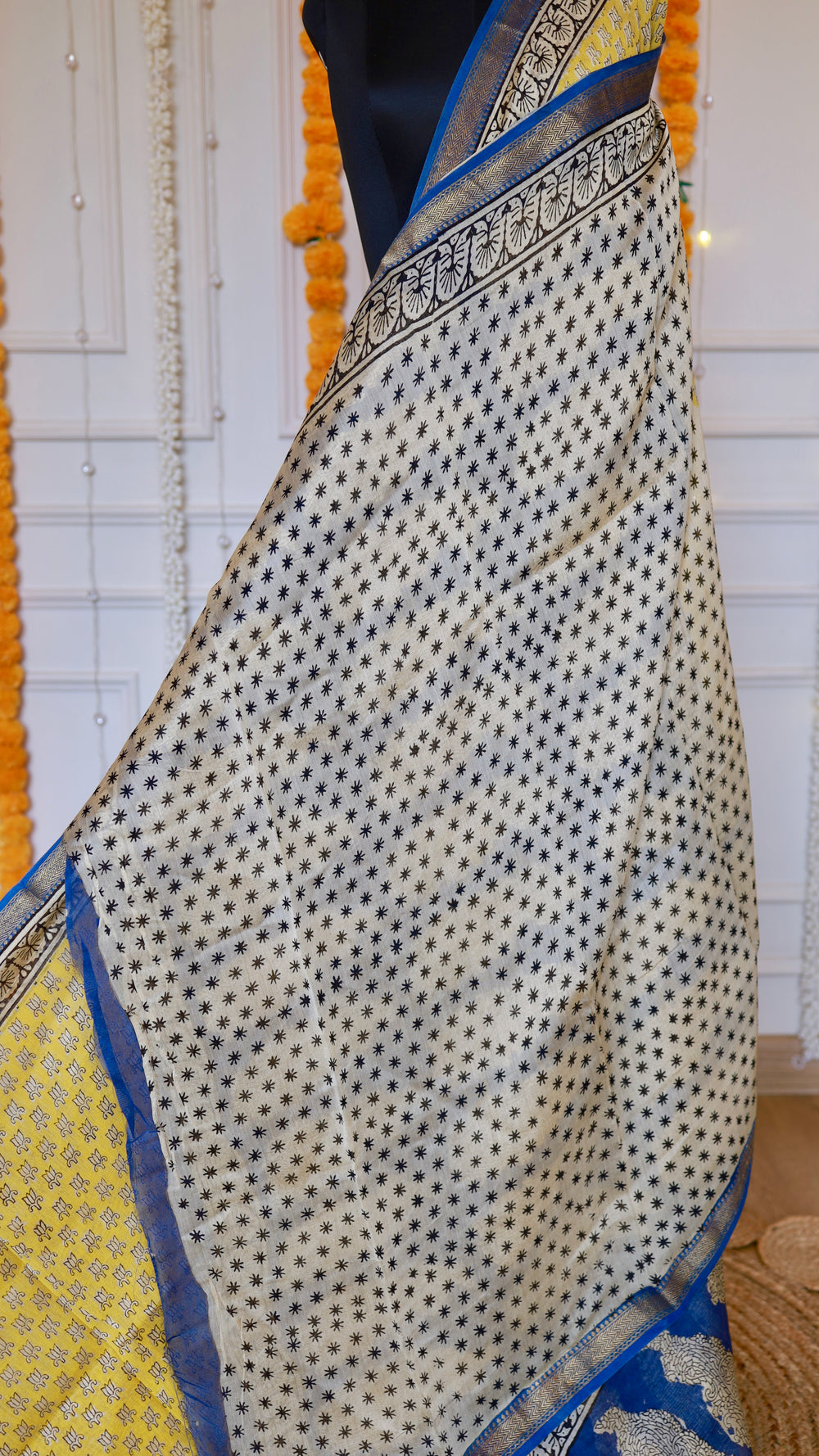 Close-up view of off-white running blouse piece with black starburst micro-prints and patterned border.