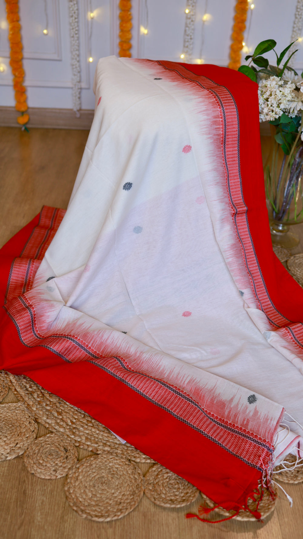 Off-white cotton Bomkai saree draped over display showcasing crimson temple border and small woven buttis