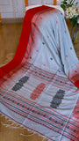Intricately woven pallu of the off-white cotton Bomkai saree displaying dark grey and red floral extra-weft motifs and traditional geometric border lines