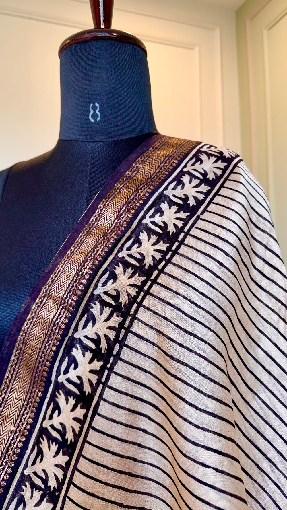 Detailed macro shot of the Zari border and leaf-patterned block print on a Maheshwari Silk Saree.