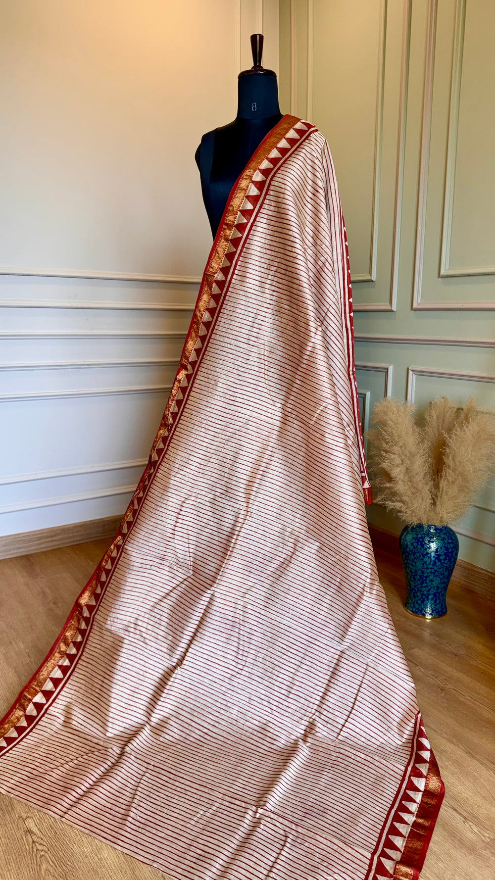 Close-up of Maheshwari Silk Saree fabric showing the intricate gold zari border and geometric triangle patterns.
