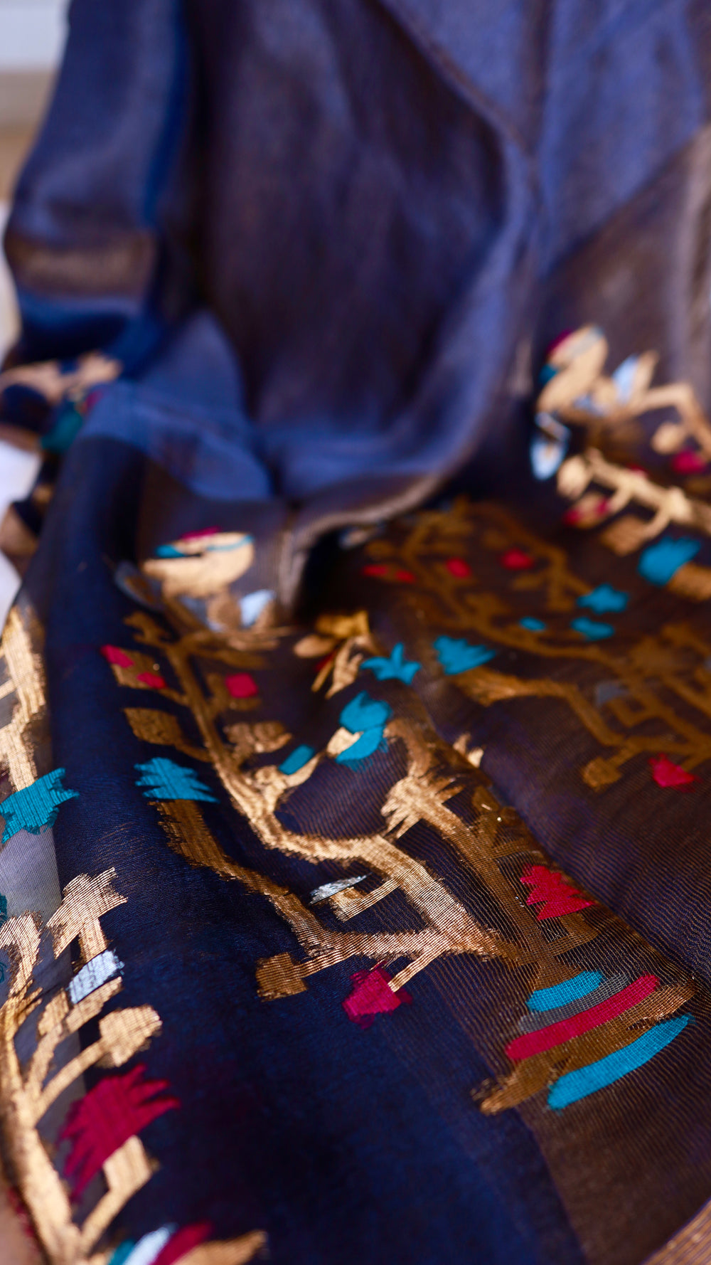 Detailed shot of turquoise and fuchsia meenakari threadwork woven into metallic gold tree patterns on pure silk linen saree.