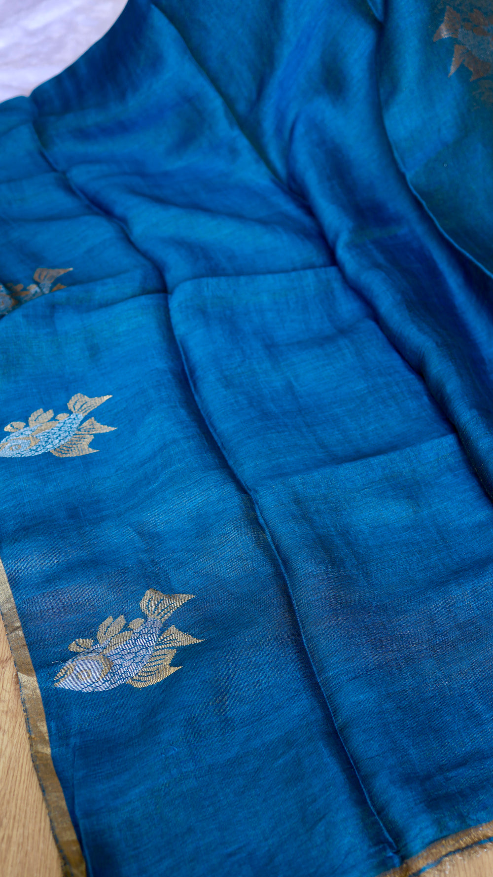 Close-up of peacock blue Pure Silk Linen Saree body showcasing woven gold and silver fish motifs.