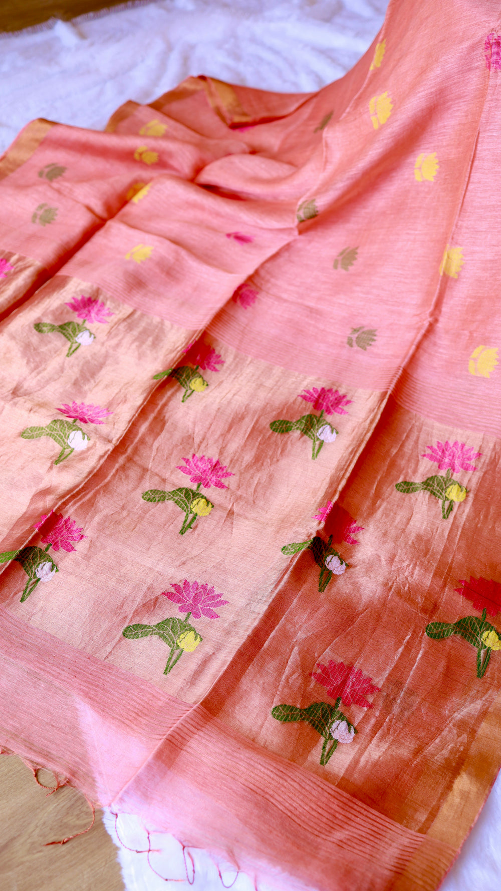 Exquisite pallu of peach coral silk linen saree densely woven with vibrant pink and green lotus motifs