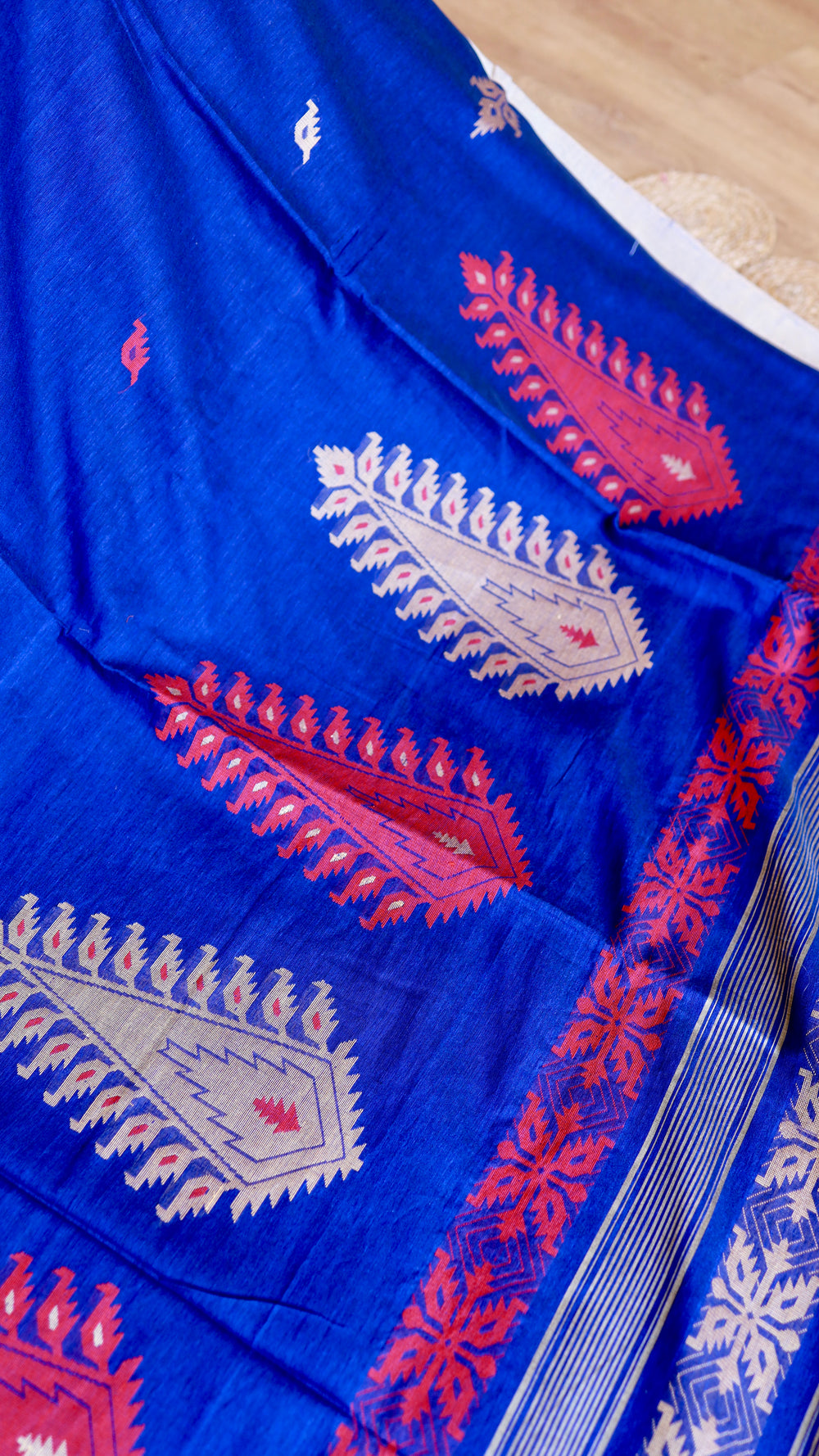 Detailed view of red and silver paisley motifs woven on a royal blue handwoven khadi cotton saree.