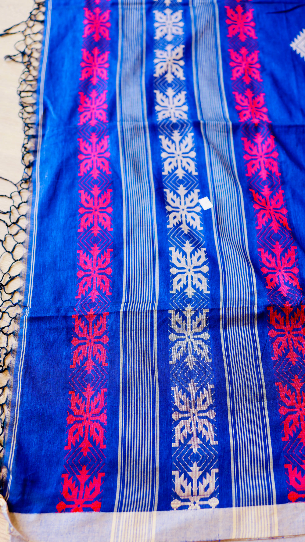 Close-up of the geometric floral woven border on royal blue handwoven khadi cotton fabric.