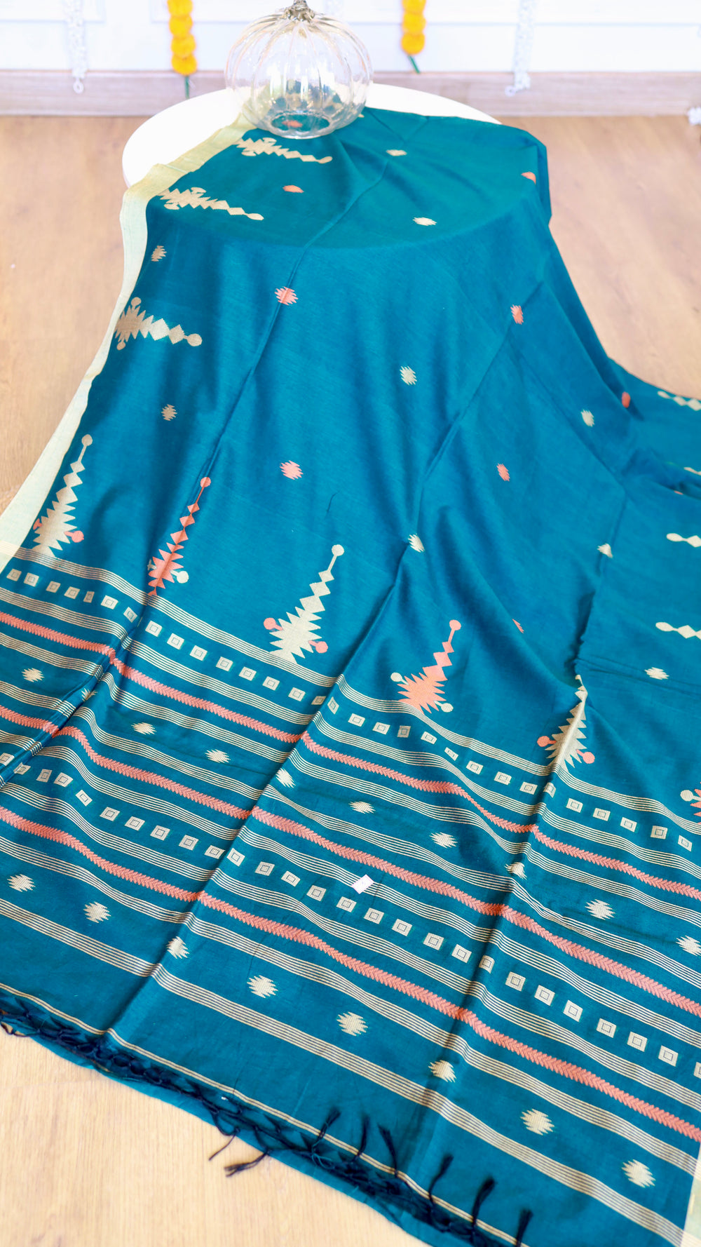 Full drape display of Peacock Teal Khadi Cotton Saree showing contrast coral geometric pallu pattern and hand-knotted fringe edges.