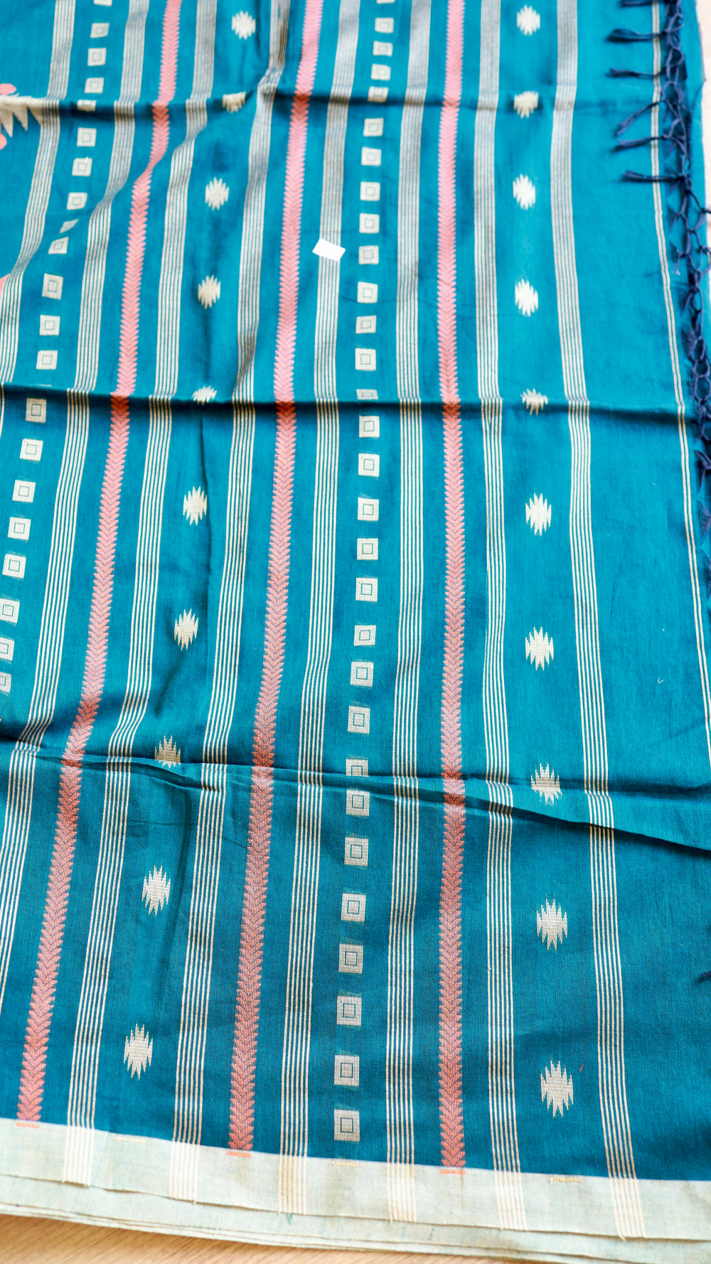 Detailed view of handwoven Peacock Teal Khadi Cotton Saree body displaying fine vertical stripes, woven star motifs, and dark blue tassels.